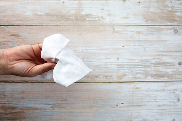 Female hand holding tissue on wooden background top view with copy space, hygienic clean concept