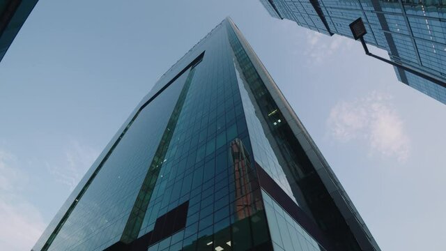 Beautiful wide angle view from below from a moving camera on tall skyscrapers buildings in a modern city business downtown. Dolly shot from passing by car