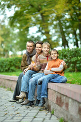 Naklejka na ściany i meble Portrait of family of four sitting in park
