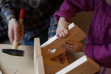 Making a wooden bird feeder. Dad and daughter are doing together. The concept of spending time...