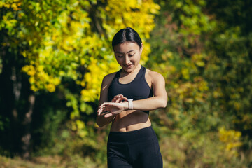Portrait of young fitness woman athlete, asian looking at camera and smiling, enjoying fitness smart watch, for fitness