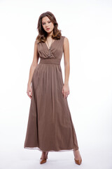 Fototapeta premium High fashion photo of beautiful elegant young woman in a pretty beige brown dress with a neckline, necklace posing on white background. Slim figure, make up, luxurious hair, shiny curls. Studio Shot