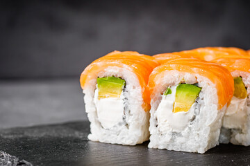 appetizing philadelphia sushi roll with salmon and avocado on a black stone plate