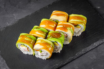 appetizing green dragon sushi roll with philadelphia cucumber shrimp and avocado on a black stone plate