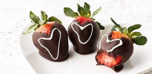 Chocolate covered strawberries decorated with hearts, and a bite out of one. 