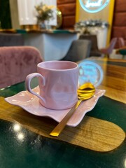 pink small cup with golden spoon