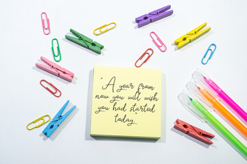 Text sign showing A year from now you will wish you had started today on Set of colorful paper clips with white copy space background.