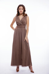 High fashion photo of beautiful elegant young woman in a pretty beige brown dress with a neckline, necklace posing on white background. Slim figure, make up,  luxurious hair, shiny curls. Studio Shot