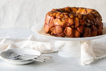 Homemade apple cinnamon monkey bread on a pedestal stand with plates for serving
