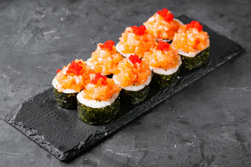 appetizing sushi roll maki with salmon on a black stone plate