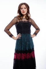 Fototapeta premium High fashion photo of a beautiful elegant young woman in a pretty triple black, red, green color dress with lace, blue shoes posing on white background. Slim figure, hair, shiny curls. Studio Shot