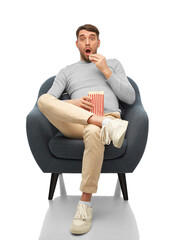people and leisure concept - surprised man eating popcorn sitting in chair over white background