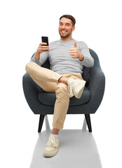 people, communication and technology concept - happy smiling man with smartphone sitting in chair...