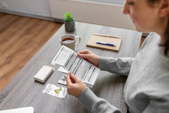medicine, quarantine and pandemic concept - hands of woman reading self coronavirus test manual at home