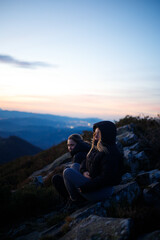 Friends enjoying a sunset on top of a mountain with their dog