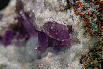macro mineral amethyst stone in rock on a black background