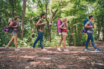 Photo of four positive sporty friends carry large backpack walk mountain hiking wear casual outfit...