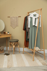 Fototapeta na wymiar Modern dressing room interior with clothing rack, wooden table and mirror