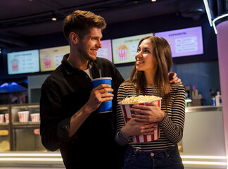 White couple smiling while eating popcorn and drinking soda together