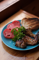 fried chicken wings, tomatoes, herbs and bread on a blue plate