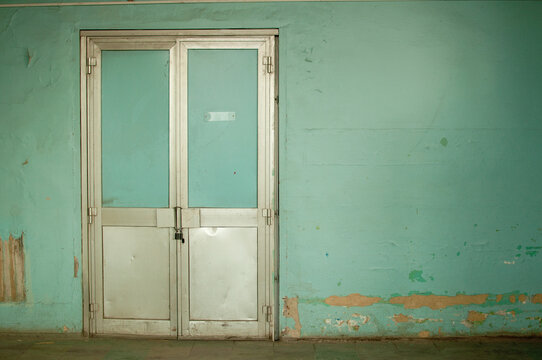 old battered metal doors with a lock on the background of a blue wall with peeling paint