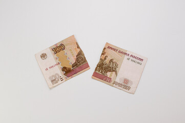 a hundred-ruble Russian banknote, torn into two parts on a white background