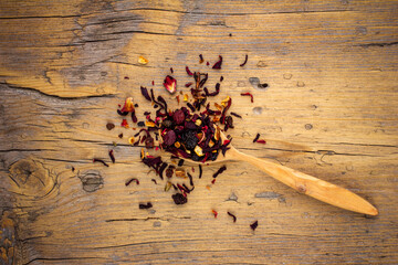 wooden spoon with dried flower berry tea on an old wooden background top view