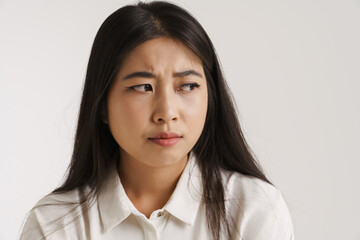 Young asian woman dressed shirt frowning and looking aside