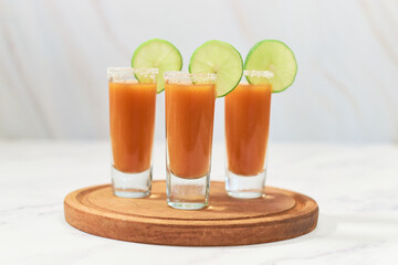 Three tequila shot with sangrita on wooden board. Mexican appetizer for tequila.