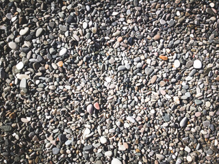 Sea stones background with small pebbles or stone in garden or in the seaside or on a beach. A close up view of rounded smooth polished pebble stones