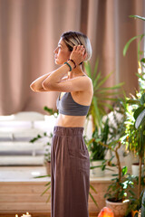 side view on slim woman standing before yoga at home, preparing to meditate, wearing domestic clothes relaxing in yoga studio or at home, stress relief. portrait of caucasian lady having rest