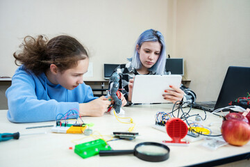Teenage group at robotics school makes and programs robot from the constructor, children learn robot constructing at STEM engineering science education class.