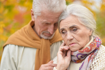 Portrait of sad senior couple in autumn park