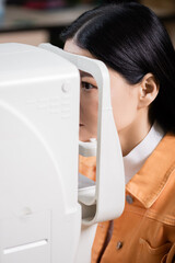asian woman examining eyesight on blurred ophthalmoscope.