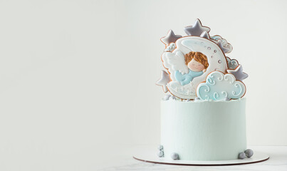Christening cake with blue cream cheese frosting decorated with gingerbread cookies on the white...