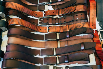 Various types of brown leather belt in a row for display and sale on the market. Realistic leather...