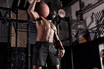 Strong man working out at indoors modern gym using medicine ball.Shirtless african male with muscular body is stretching with cross fit ball. sport, fitness, weight loss, cross fit concept