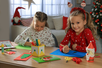 Cute little children making beautiful Christmas greeting cards at home