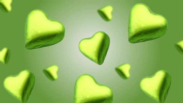 Flying A heart shape wrapped chocolate candy flying and wiggle of different diameters on a trending turquois gradient background. High quality 4k UHD footage.