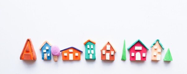 a row of rustic colorful cute houses and trees made of plasticine. isolate on white background..