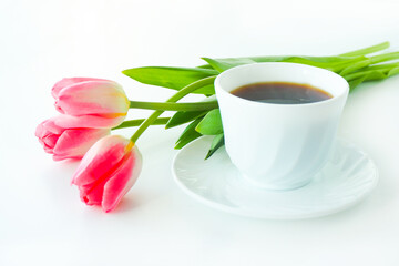 Fototapeta na wymiar three pink tulips and a cup of coffee on a white table..