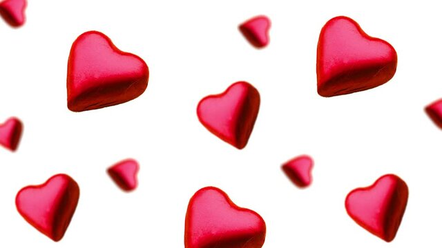 A stream of many different diameters heart shape wrapped colorful chocolate  candy flying on a white color background.Romantic template Love concept for mother's, St. Valentine's and women's  Day