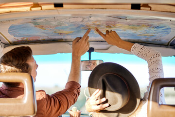 Summer travel concept. young friends or couple looking at map above to plan a camper van trip pointing finger at map. vacation, holidays, adventure, journey, trip, travel concept. rear view - Powered by Adobe