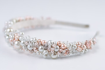 Blurred image of a hairband with white and pink pearls on a light background.