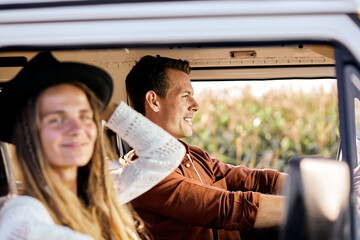 happy caucasian man and woman couple drives an old vintage camper van on road. Family travel vacation and holiday trip. Side view. Focus on smiling guy, in countryside, adventure and travel