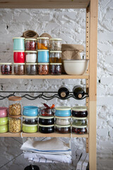 Assortment of grains, cereals and pasta in glass jars and dry herbs on wooden shelf. Healthy balanced food ingredients, zero waste storage idea, eco friendly concept.