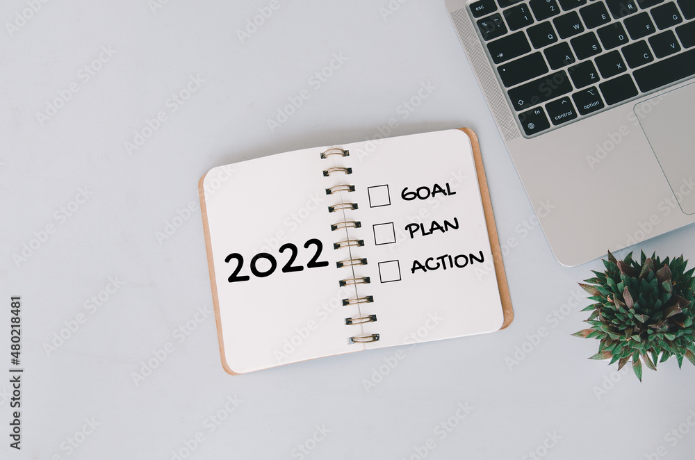 Poster 2022 new year goal,plan,action concepts with text on notepad and computer laptop on background.