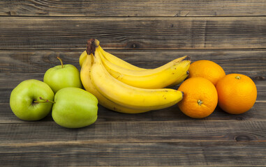 Green apples, bananas, oranges on wooden background. - Powered by Adobe