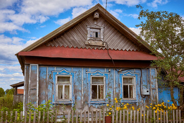 A traditional old wooden house with a front garden. Summer view.