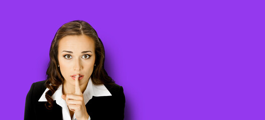 Portrait of young serious business woman keeping finger on her lips and asking to keep quiet,...